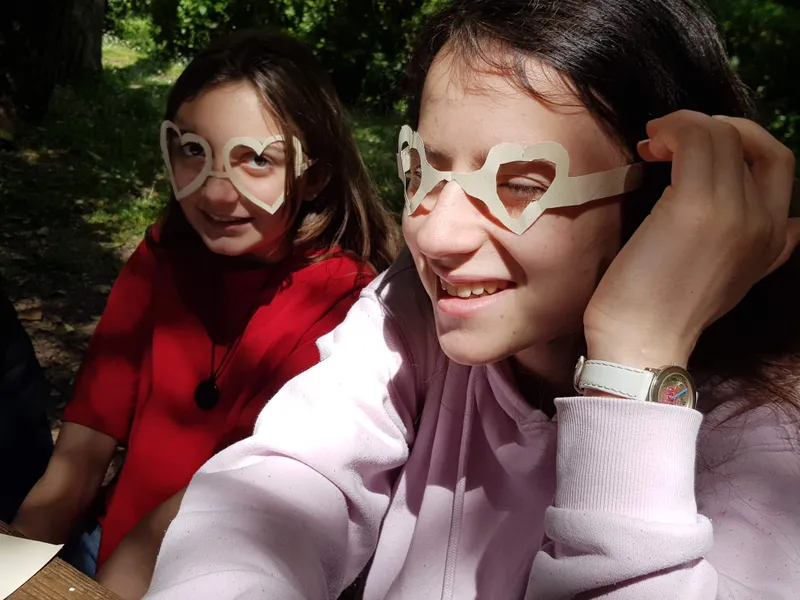 Deux jeunes de l'aumônerie avec des lunettes en carton en forme de cœur